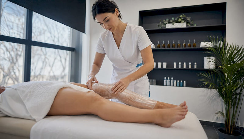 Specialistul aplică un tratament cu împachetări corporale într-un centru spa, pentru relaxare și revitalizarea pielii.