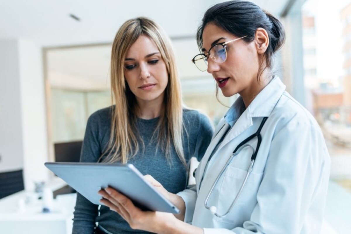 Medic care discută cu o pacientă, cu o tabletă în mână